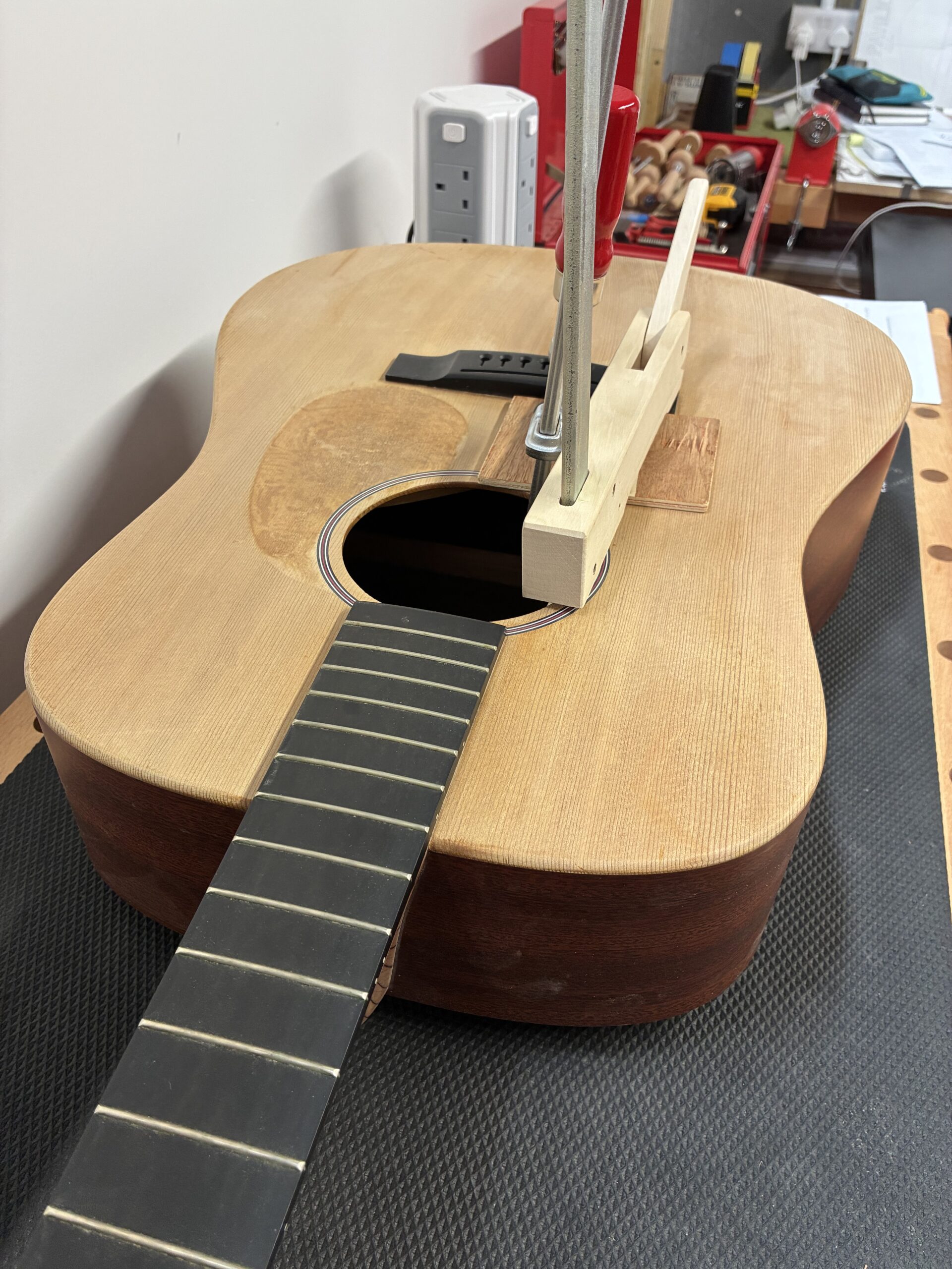 An image showing an acoustic guitar in the process of being repaired